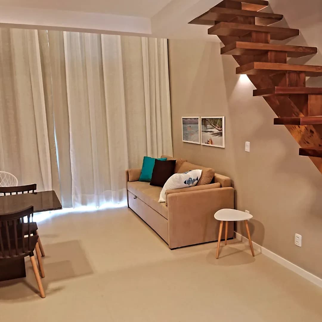 Sala de estar com escada de madeira e paredes claras, obra entregue pela Ideal Pinturas