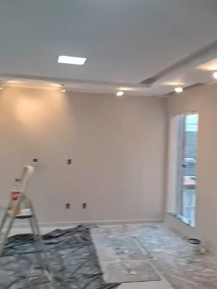 Obra em andamento: piso e móveis protegidos, escada montada e parede sendo pintada